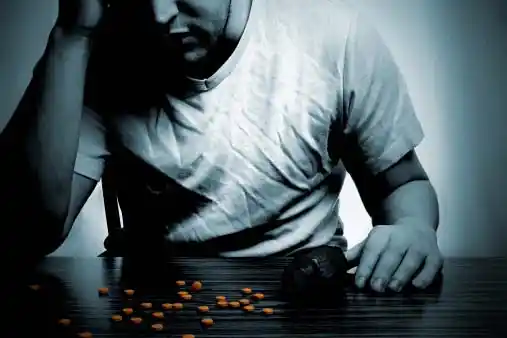 depressed young man looking at the pills scattered in front of him